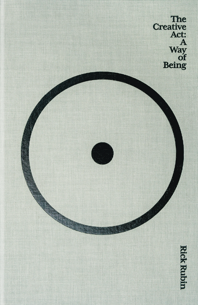 A book cover containing a black circle surrounding a black dot on a linen material.